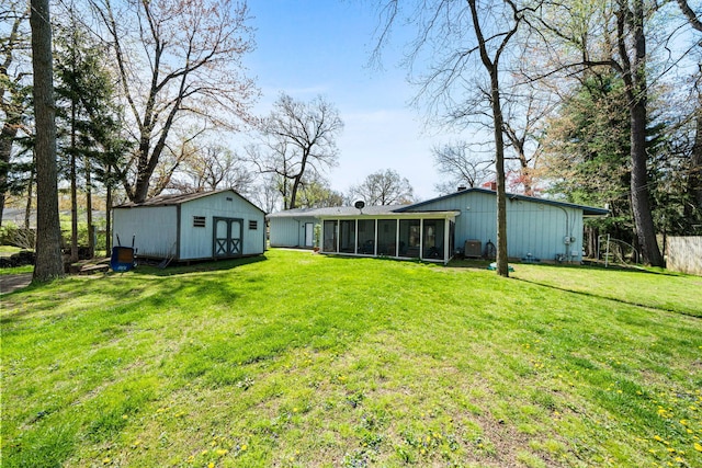 rear view of house featuring a sunroom, a lawn, an outbuilding, and a storage unit