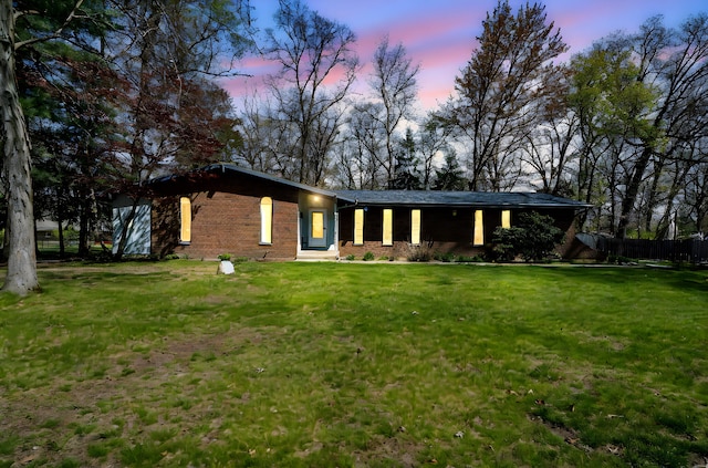 view of front of property featuring brick siding, fence, and a front yard