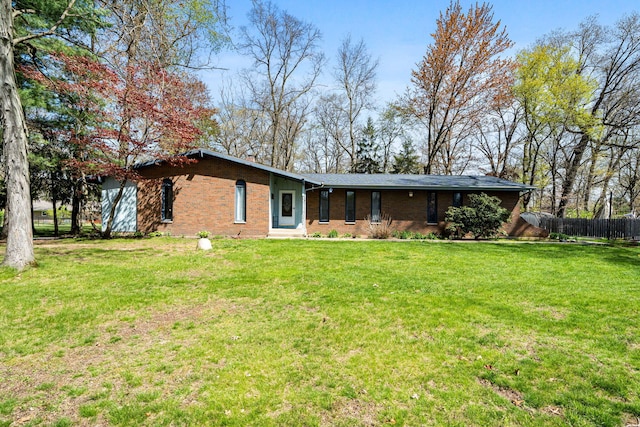 back of house with a lawn, brick siding, and fence