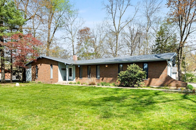 view of front of house with a chimney, a front lawn, and brick siding