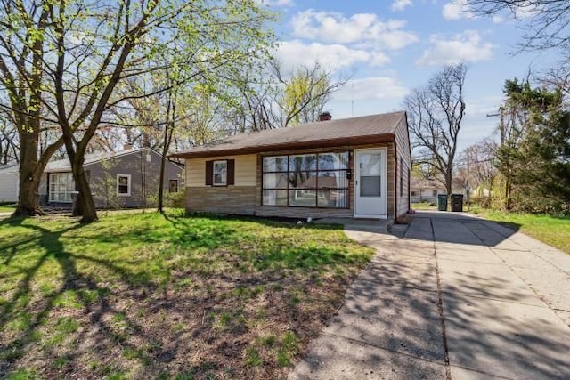 rear view of property with a lawn, a chimney, and driveway