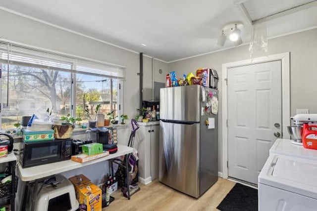 kitchen featuring light wood-type flooring, freestanding refrigerator, washing machine and dryer, and black microwave