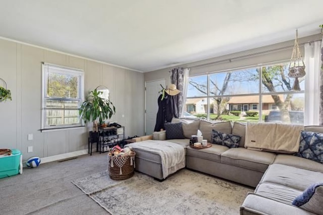 living area with carpet flooring, ornamental molding, and a decorative wall