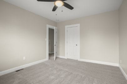 carpeted empty room with baseboards, a ceiling fan, and visible vents