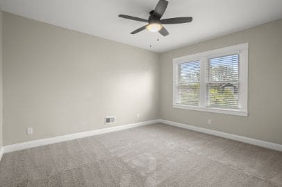 carpeted spare room featuring baseboards, a ceiling fan, and visible vents