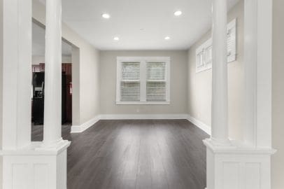 unfurnished living room with ornate columns, recessed lighting, and dark wood-style floors