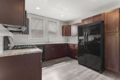 kitchen with a sink, range, recessed lighting, light wood-type flooring, and black fridge with ice dispenser