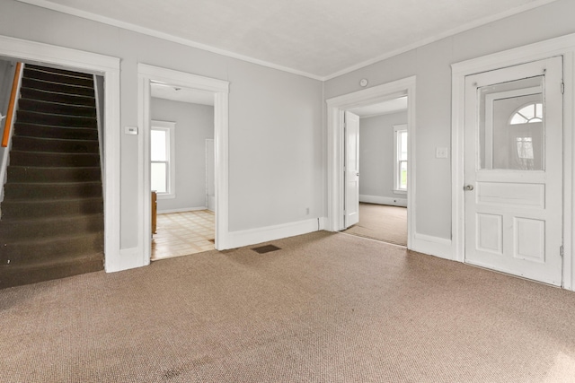unfurnished living room with visible vents, carpet, crown molding, and baseboards