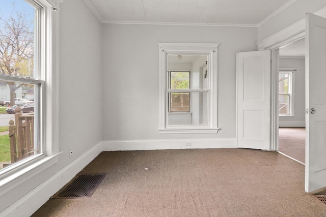 carpeted spare room featuring visible vents, ornamental molding, baseboards, and plenty of natural light