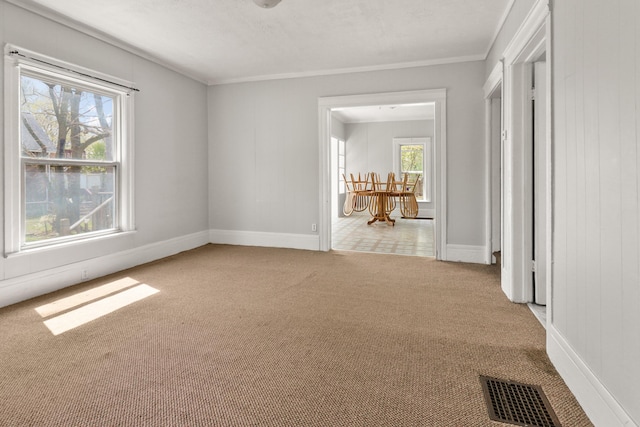 unfurnished room with crown molding, baseboards, carpet, and visible vents