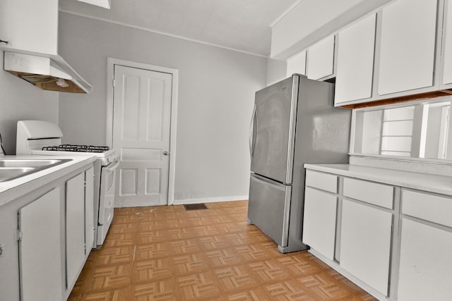 kitchen with crown molding, light countertops, white gas range oven, freestanding refrigerator, and white cabinets