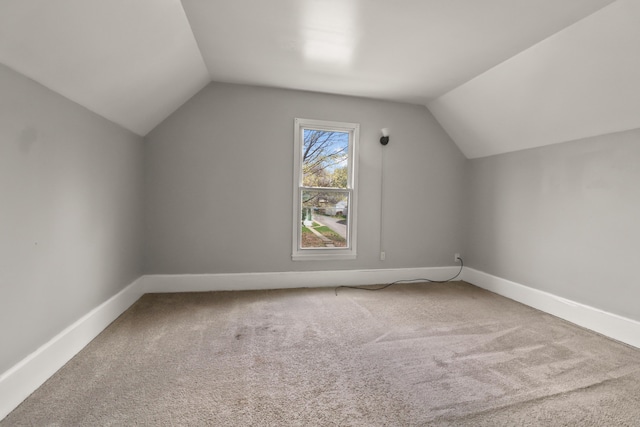 additional living space featuring carpet floors, baseboards, and lofted ceiling