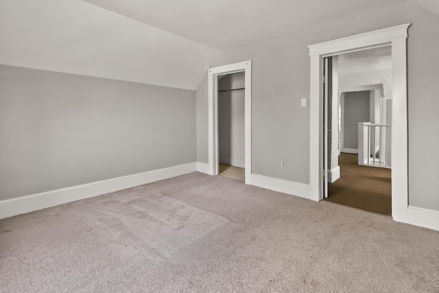 unfurnished bedroom with carpet flooring, baseboards, lofted ceiling, and a closet
