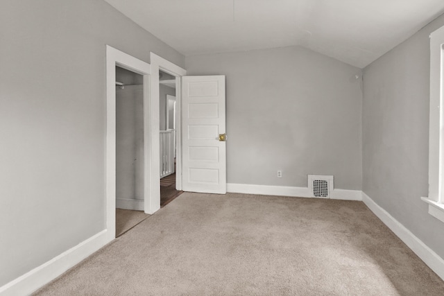 unfurnished bedroom featuring visible vents, carpet, baseboards, and vaulted ceiling