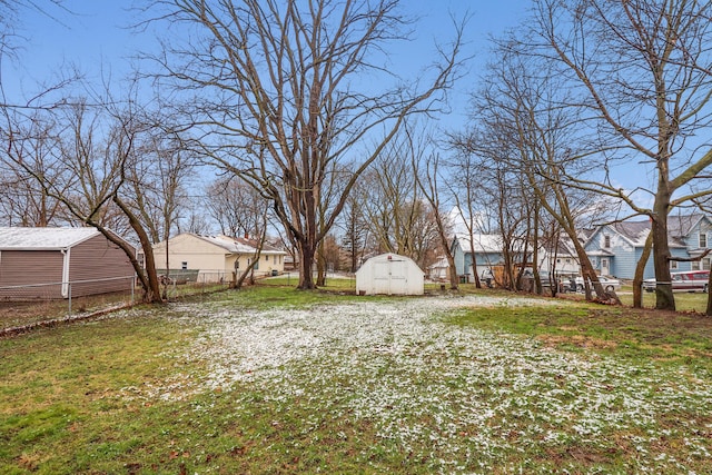 view of yard featuring an outdoor structure, a storage unit, fence, and a residential view