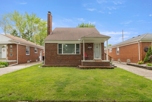 view of front of house with brick siding, a chimney, and a front yard