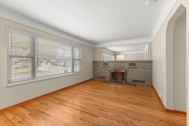 unfurnished living room with baseboards, wood finished floors, and a fireplace with flush hearth