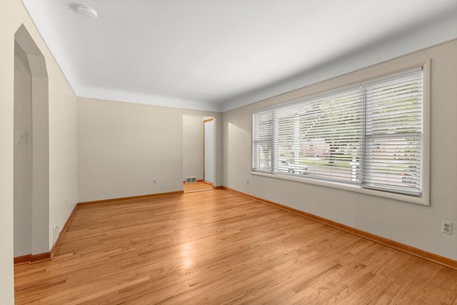 unfurnished room featuring light wood-style floors, baseboards, and a smoke detector