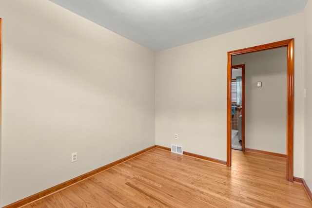 spare room featuring light wood-type flooring and baseboards