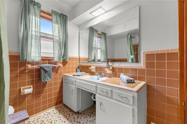 bathroom with tile walls, a wainscoted wall, vanity, and tile patterned floors