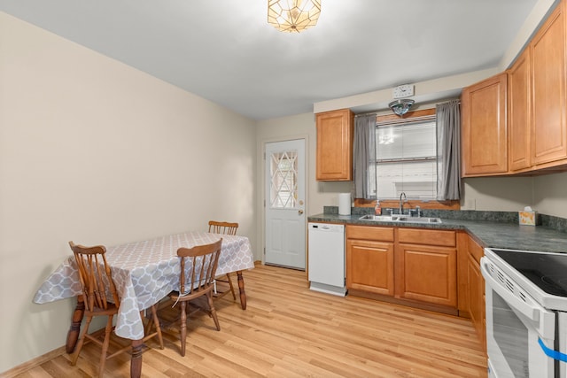 kitchen featuring a sink, white appliances, dark countertops, and light wood-style floors