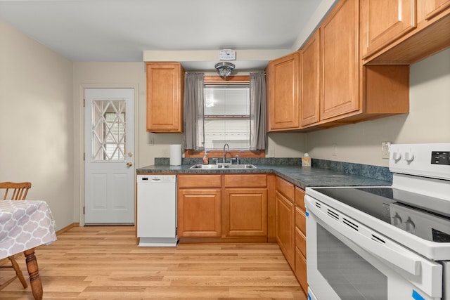 kitchen with white appliances, a sink, dark countertops, and light wood finished floors