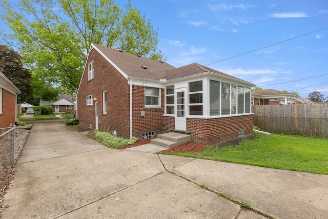 bungalow-style home featuring brick siding, roof with shingles, and a sunroom