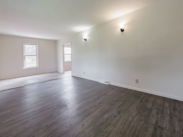 unfurnished room with visible vents, dark wood-style flooring, and baseboards