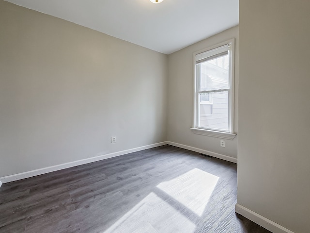 spare room with baseboards, dark wood-style floors, and visible vents