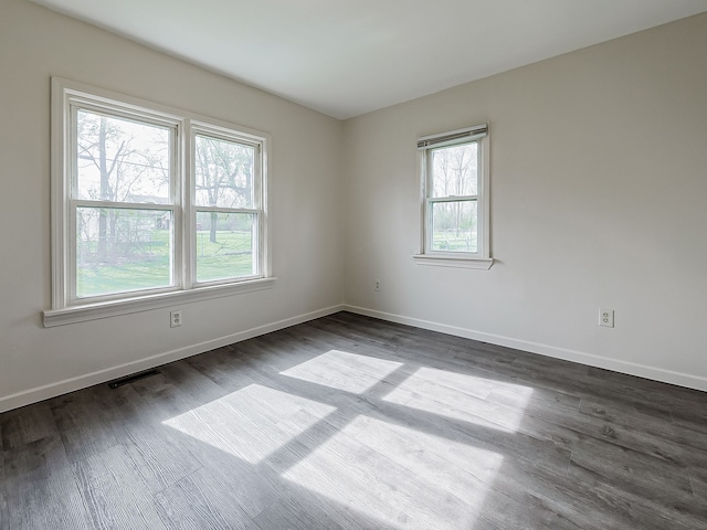 unfurnished room featuring dark wood-style flooring, baseboards, and visible vents