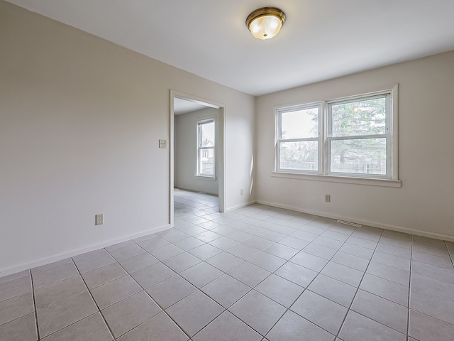 empty room with light tile patterned floors, baseboards, plenty of natural light, and visible vents