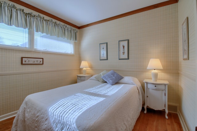 bedroom with crown molding, baseboards, visible vents, and wood finished floors