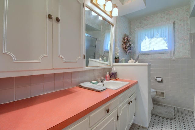 bathroom with toilet, wallpapered walls, tile walls, visible vents, and a stall shower