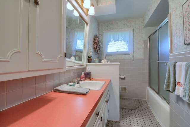full bathroom featuring tile walls, tile patterned floors, vanity, combined bath / shower with glass door, and wallpapered walls