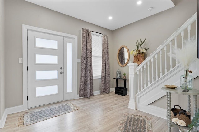 entryway featuring baseboards, light wood-type flooring, stairs, and a wealth of natural light