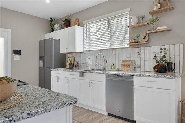 kitchen featuring stainless steel dishwasher, open shelves, white cabinetry, a sink, and backsplash