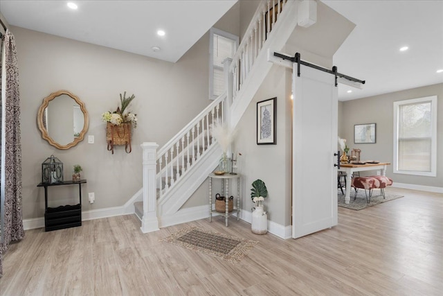 stairway with recessed lighting, a barn door, baseboards, and wood finished floors