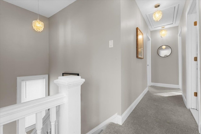 hallway with baseboards, carpet, attic access, and an upstairs landing