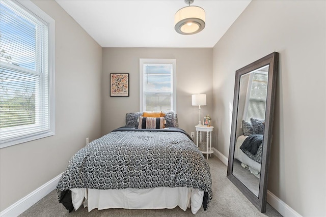 carpeted bedroom featuring baseboards and multiple windows