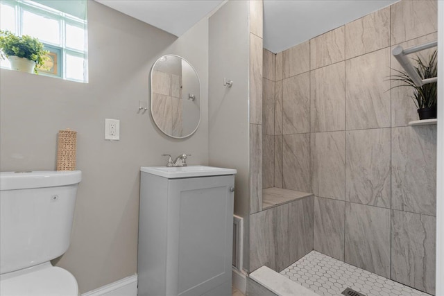 bathroom with vanity, a tile shower, and toilet