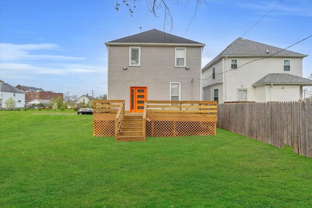 rear view of house featuring a lawn, a deck, and fence