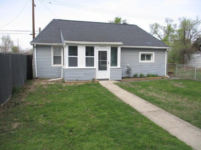 bungalow with roof with shingles, a fenced backyard, and a front yard