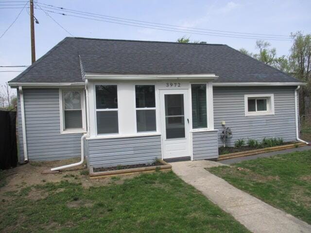 bungalow with a shingled roof and a front yard
