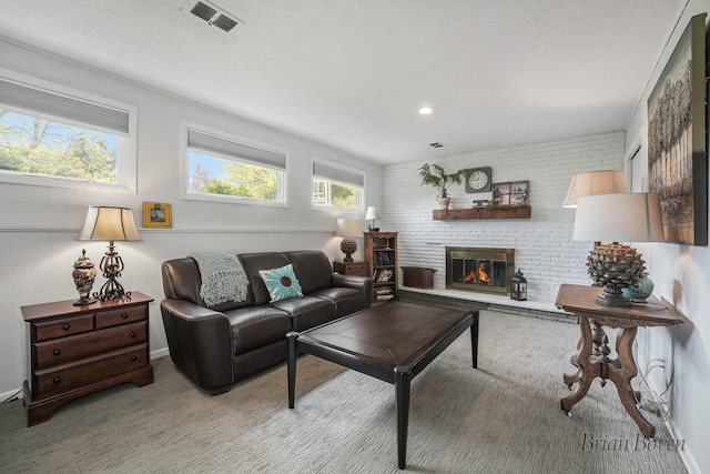 living area featuring a brick fireplace and visible vents