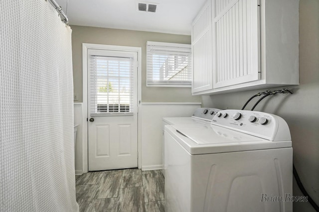 laundry room with visible vents, cabinet space, wood finished floors, and washing machine and clothes dryer