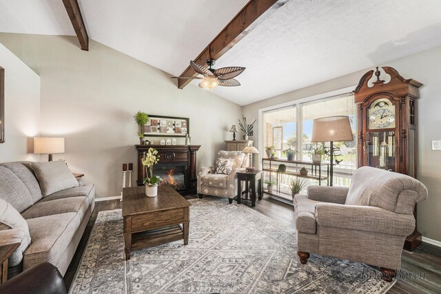living room with a glass covered fireplace, a ceiling fan, baseboards, vaulted ceiling with beams, and wood finished floors