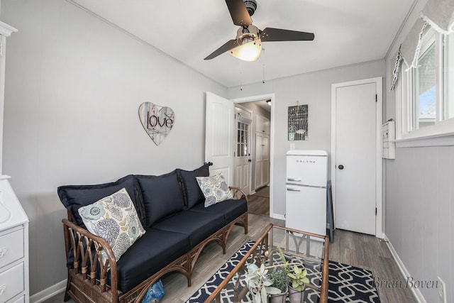 living room with baseboards, a ceiling fan, and wood finished floors