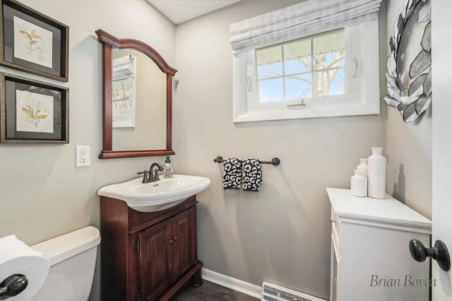 bathroom featuring vanity, toilet, baseboards, wood finished floors, and visible vents