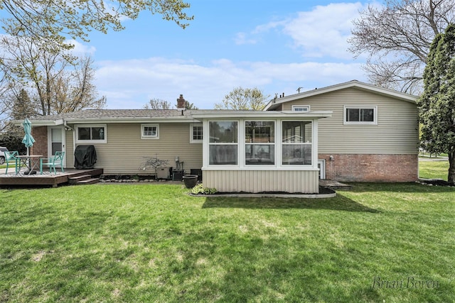 back of property with a yard, a wooden deck, a sunroom, and a chimney