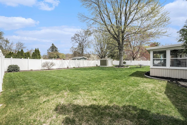 view of yard featuring a storage unit, a fenced backyard, an outbuilding, and a sunroom